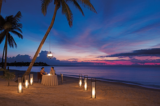 couple having dinner on beach at sunset