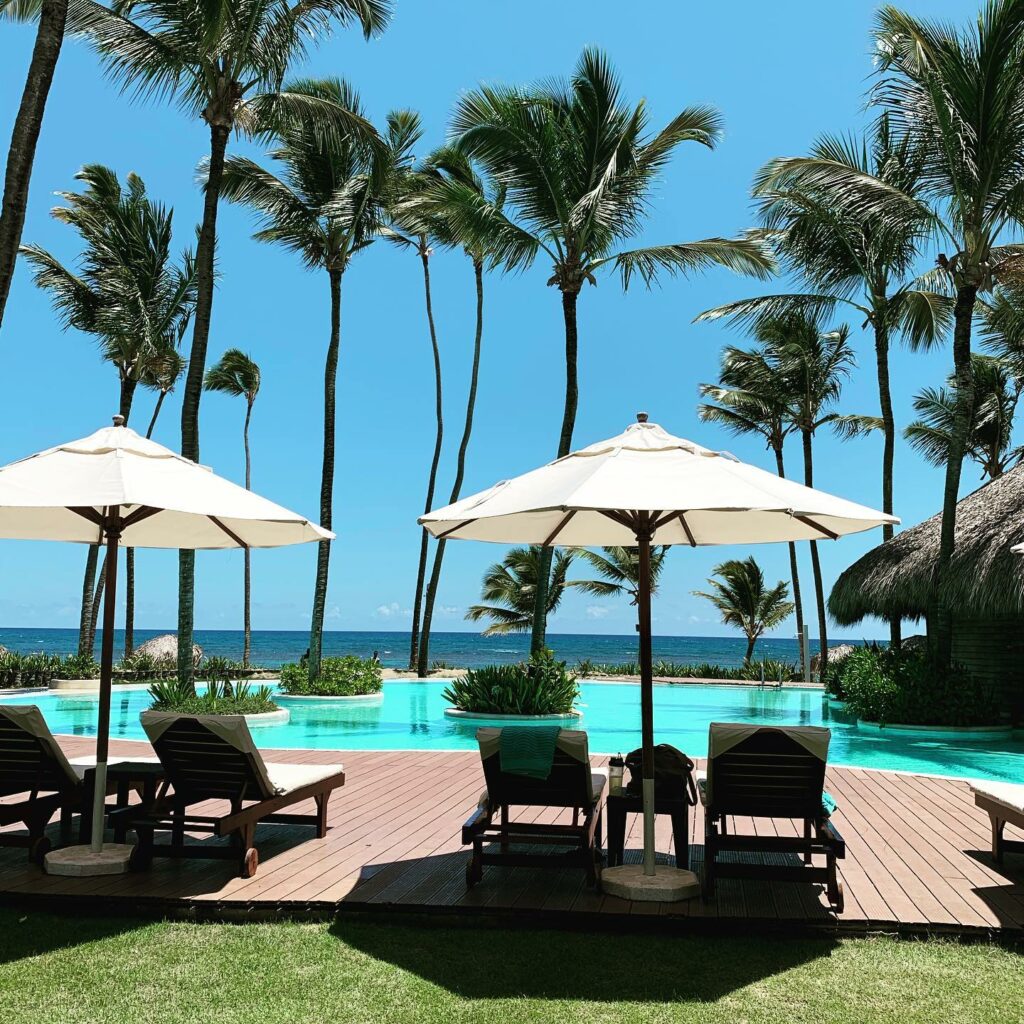 ocean, pool, umbrellas, and palm trees